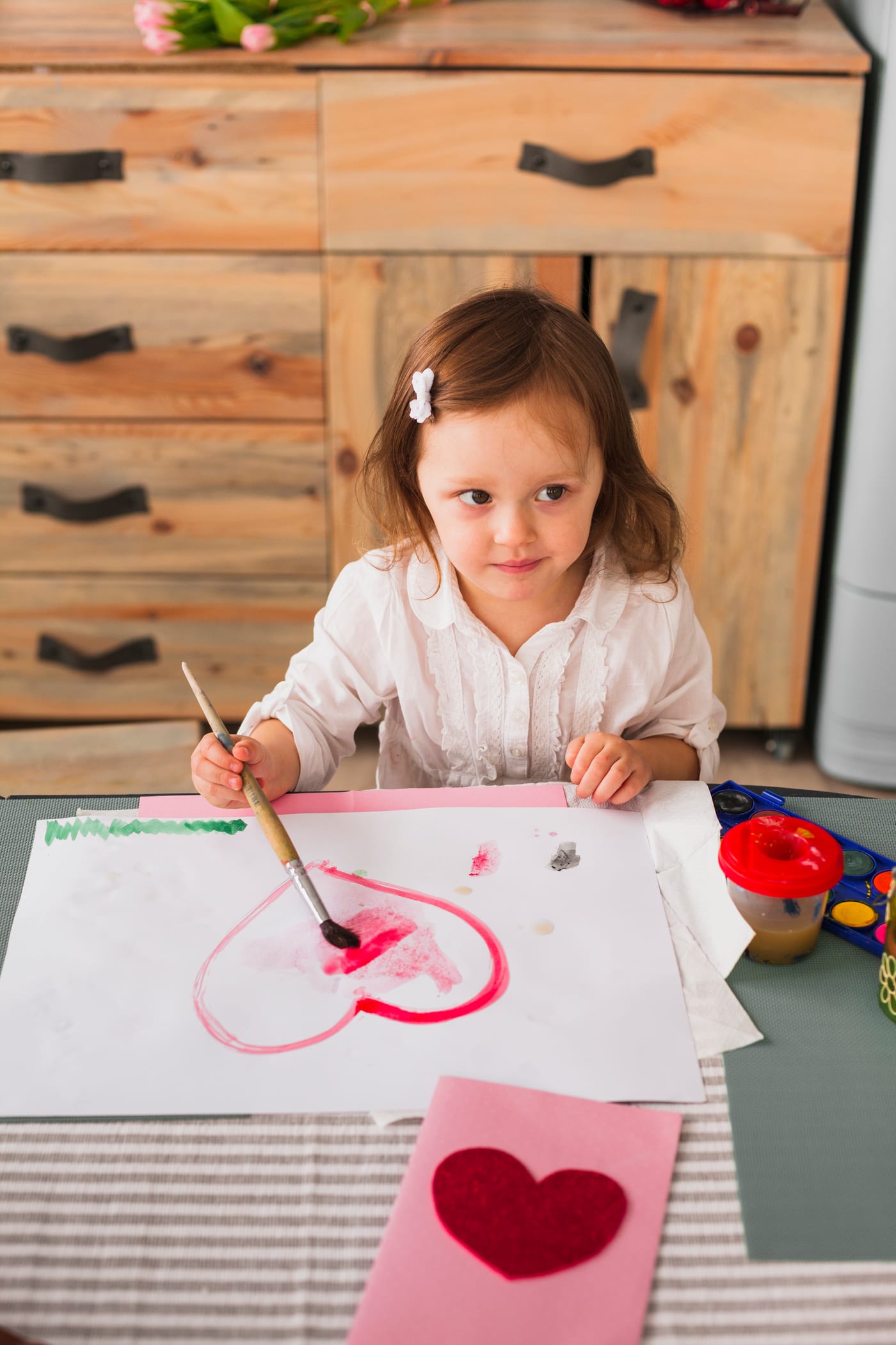 A young girl painting a heart with watercolours