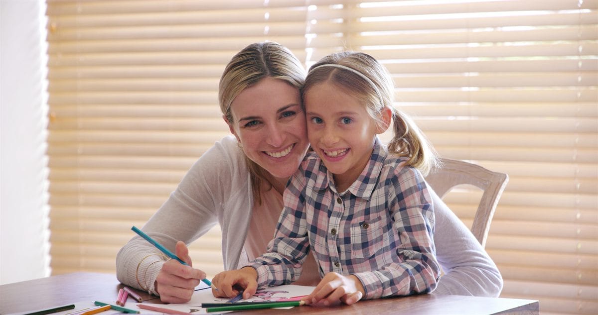 A mother and daughter drawing together with color pencils at home