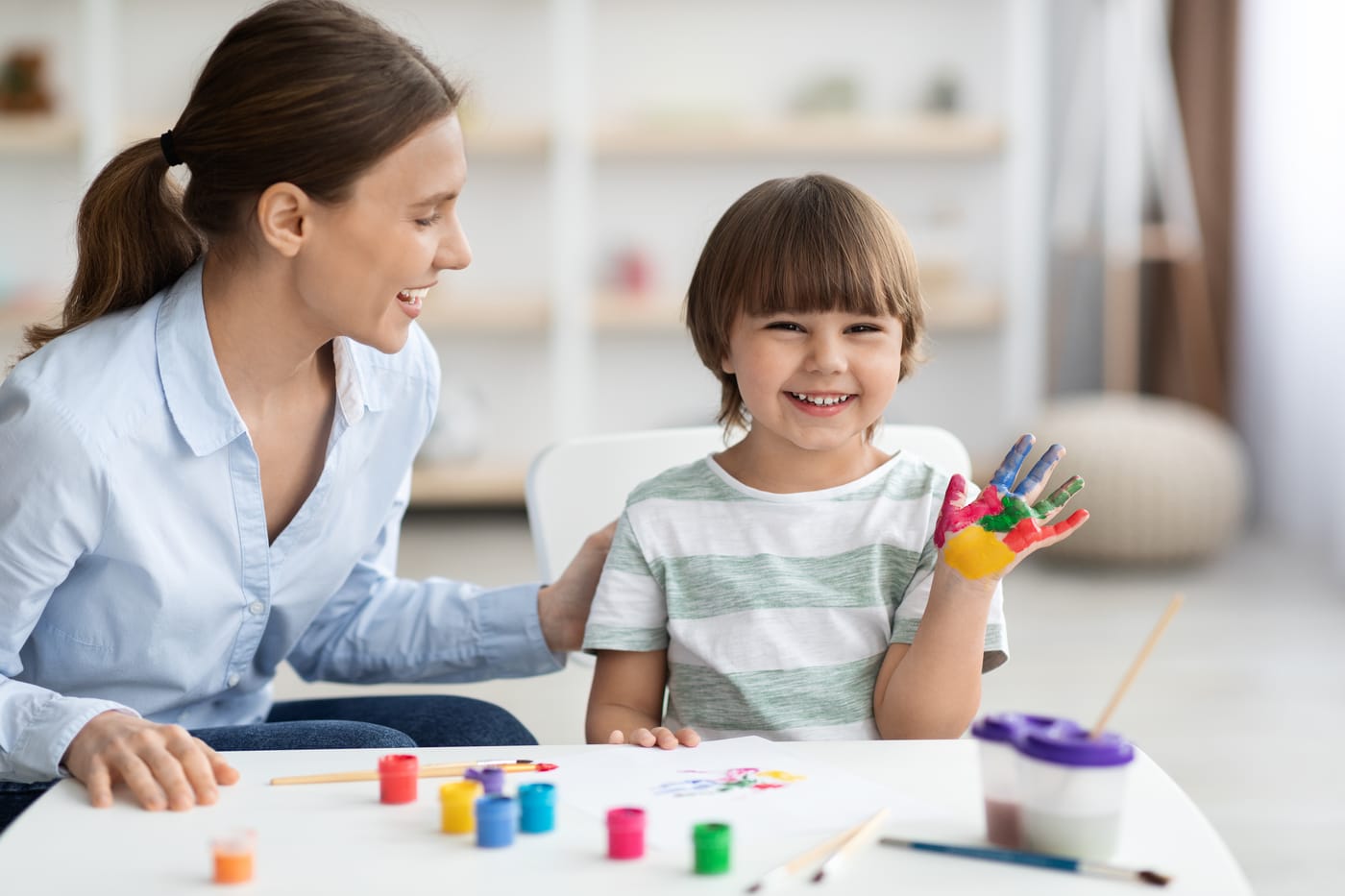 A therapist and a smiling child at a table during an art activity